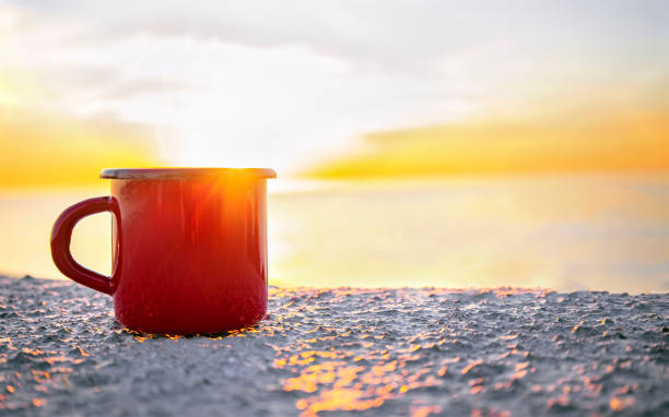 tasse rouge sur le lever du soleil - at the beach photos et images de collection