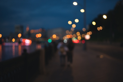 Blurred abstract image, urban background and texture. Couple hugs and walks along the embankment at night city
