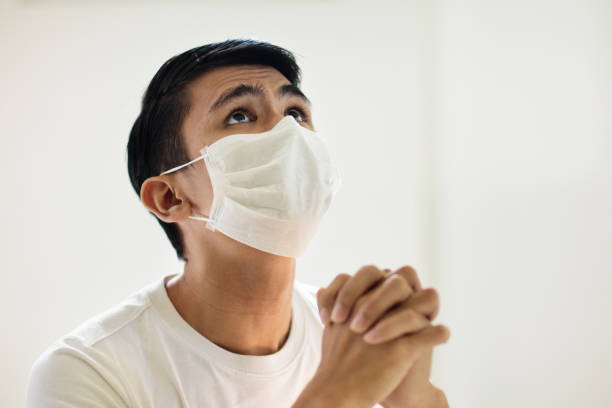 istock Asian man in face mask praying for coronavirus victim 1283855288