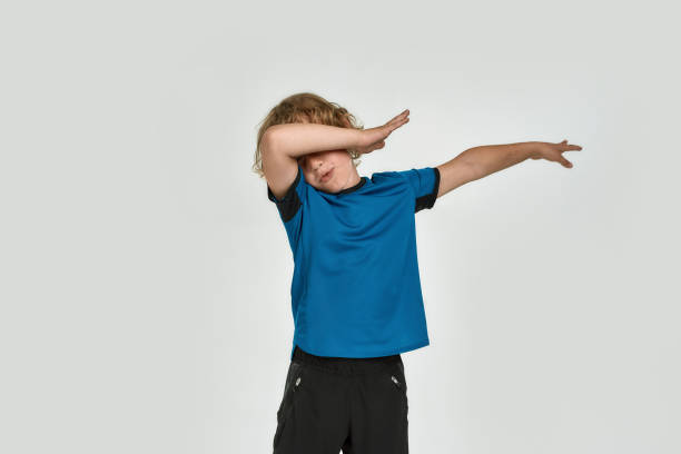 istock Cheerful little sportive boy child in sportswear doing dab dance move, gesture while posing, standing isolated over white background 1283858434