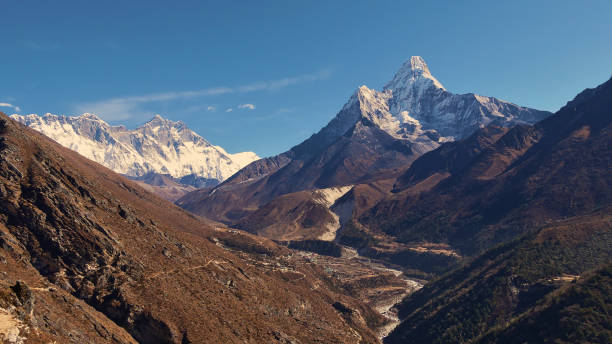 Spectacular panorama view of Sherpa village Pangboche (Panboche) in valley below majestic snow-capped mountain Ama Dablam and Mount Everest massif in the Himalayas, Nepal. stock photo