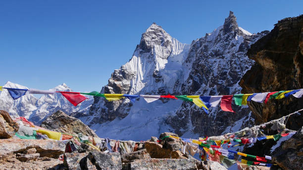 氷をかぶった山々を背景に、ネパールのヒマラヤ山脈、レンジョ・ラ・パスの頂上で、冷たい風の中で平和的に手を振るカラフルな仏教の祈りの旗。 - renjo la ストックフォトと画像