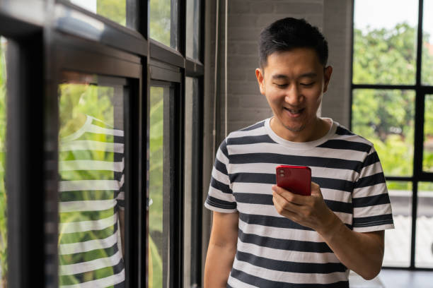 istock Asian man holding smart phone on his hands with copy space at home 1283864778