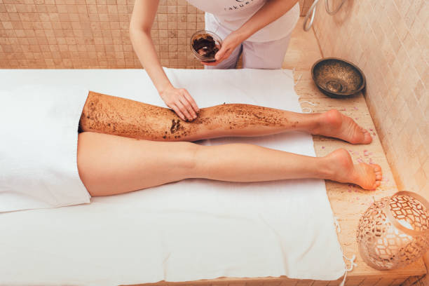 masseur apply a mud scrub to a woman's legs. the peeling procedure for a woman will make her legs smooth. - mud spa treatment health spa massaging imagens e fotografias de stock