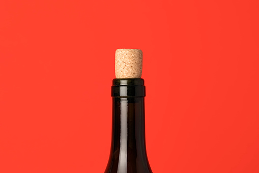 Close up of wine bottle with cork. Wine cap on red background. Minimal concept