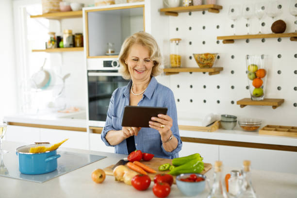 istock Senior woman using digital tablet in the kitchen, looking for recipe on internet 1283869479