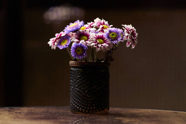 Colorful chamomile flowers in black vase on table, background with copy space. Romantic chamomile flowers