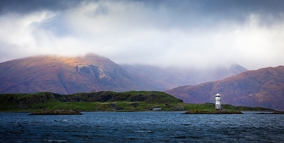 Ennerdale Lake, Cumbria in the Lake District with overcast storm clouds over the fells and the sun breaking through in the foreground