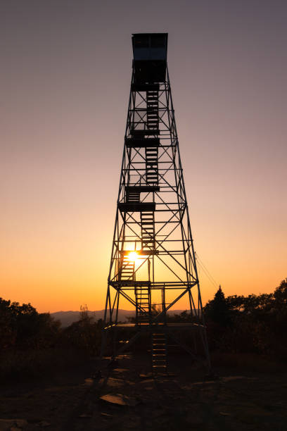 Photo of Steep stairs leading up a mountain fire tower as the sun sets on the horizon. Overlook Mountain, NY