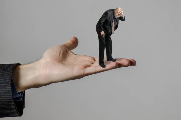 istock Business man standing in huge hand and looking down 1283874008