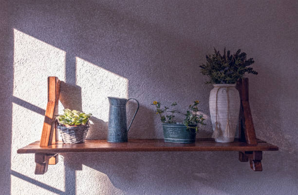 Beautiful home decor in a gentle vintage style of French Provence. Wooden wall shelf with flower pots, a vase with lavender flowers and an old-fashioned watering can. Wall decoration in the living room or dining room