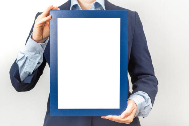 mockup diploma. woman dressed in a business suit holds a mockup of a diploma in front of her woman dressed in a business suit holds a mockup of a diploma in front of her. Certificate, diploma, picture, gratitude blue blank frame mockup information sign photos stock pictures, royalty-free photos & images