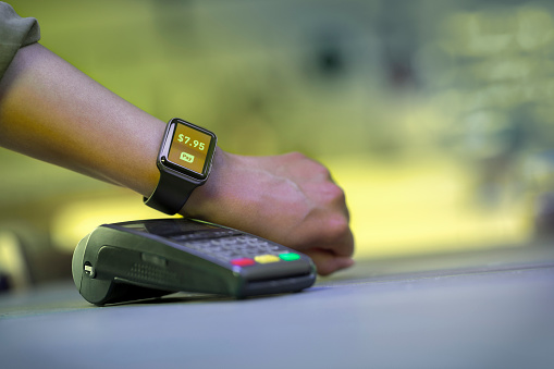 Close up of woman's hand making contactless payment with a smartwatch.