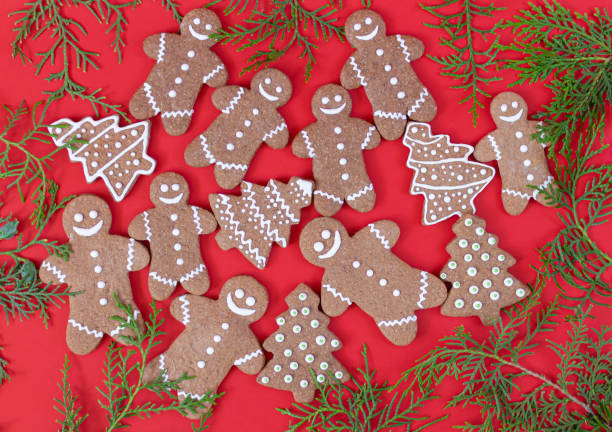 istock Homemade xmas gingerbread cookies and green branches on red table 1283881011
