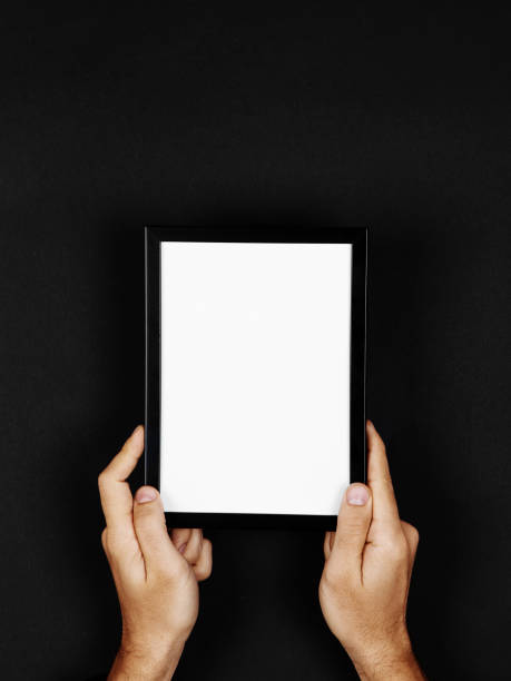istock Photo frame in hands on a black background. Preparation for text, mockup, copy space. 1283882145