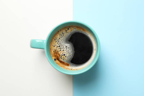 istock Cup of coffee on two tone background, top view 1283882182