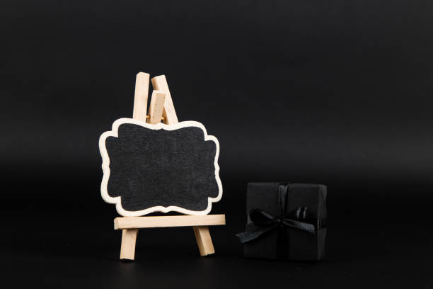 istock Black gift and mockup frame, on paper black background. Dark design concept, sales. Copy space. 1283882227