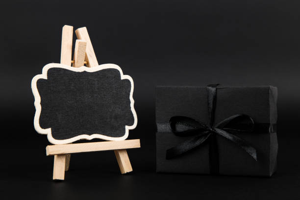 istock Black gift and mockup frame, on paper black background. Dark design concept, sales. Copy space. 1283882228