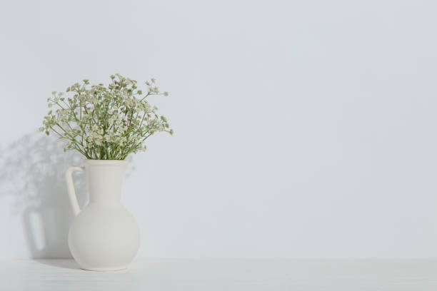 istock A vase with flowers on the table, on a white background. Light stylish design. 1283883306