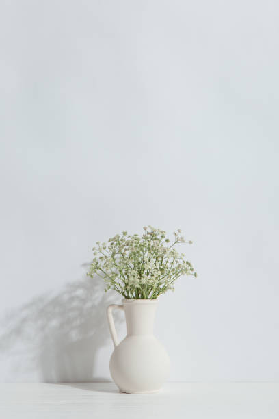 istock A vase with flowers on the table, on a white background. Light stylish design. 1283883308