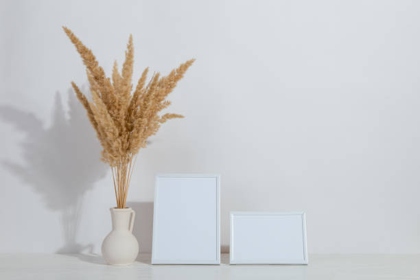 istock A vase with yellow spikelets and a white photo frame on the table. Light stylish background. Preparation for inscriptions, copy space. 1283883320