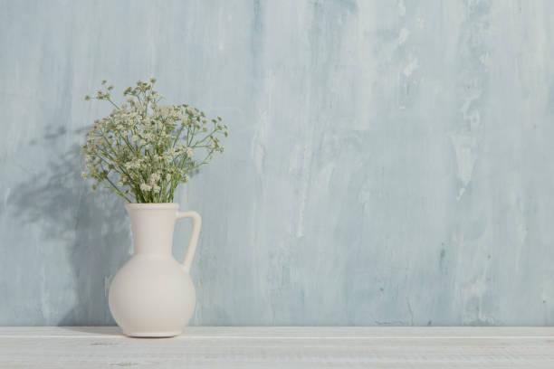 istock A vase with flowers on the table, on a blue background. Light stylish design. 1283883340