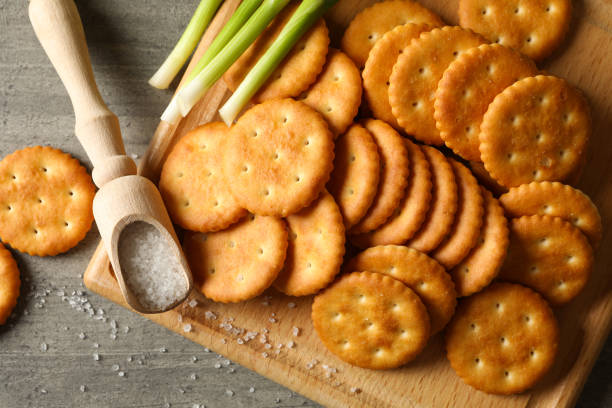 istock Board with crackers, salt and onion on gray background, close up 1283883733