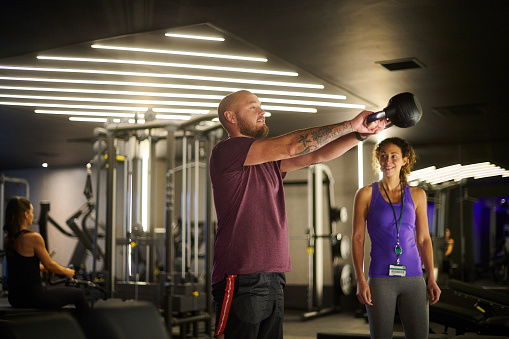 man with personal trainer with kettle bell at the gym