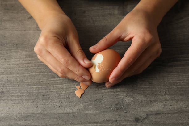 istock Woman peeling boiled egg on gray background 1283885469