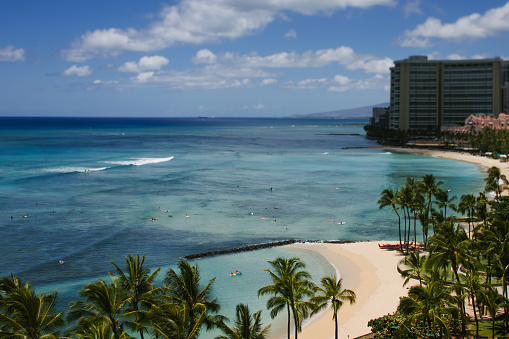 People surfing and floating in the blue water of Waikiki Beach, Hawaii in Honolulu, HI, United States