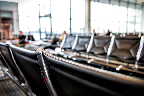 Empty black airport chairs against a wall.