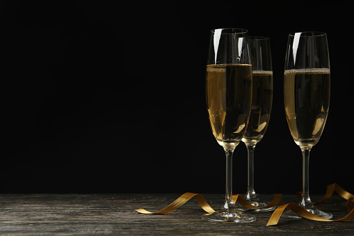 Glasses of champagne and curly ribbons on wooden table