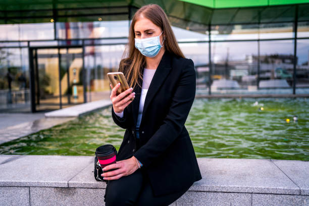 istock Businesswoman with face mask using mobile phone 1283894504