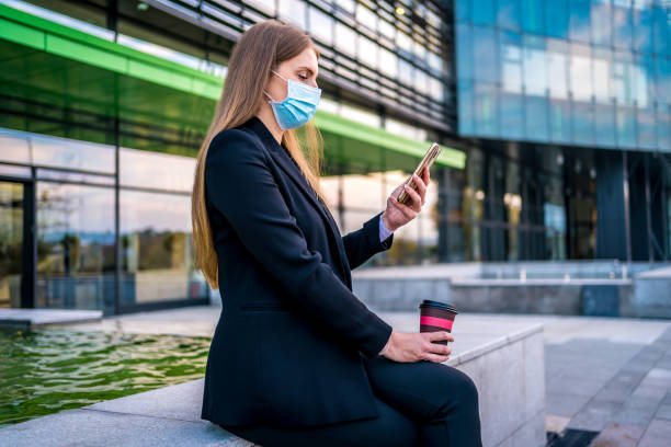 istock Businesswoman with face mask using mobile phone 1283894676