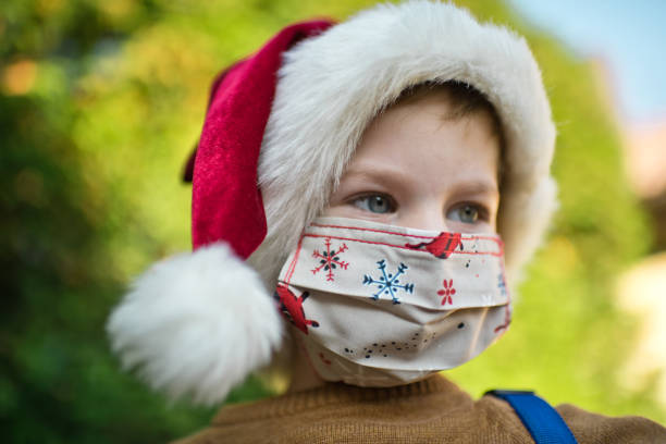 istock Little boy wearing protective face mask and Santa hat outdoors on Christmas 1283898426