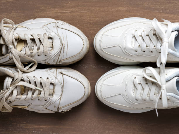 Pair of old dirty white sneakers in front of new clean one on a brown background. Past and future, old and new concepts. Comfortable shoes for active lifestyle, fitness and sports. stock photo