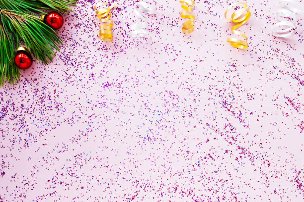 istock Christmas tree branch toys and pink sequins scattered on a pink background, flat layout, copy space. New year's background or greeting card. Christmas concept 1283899794