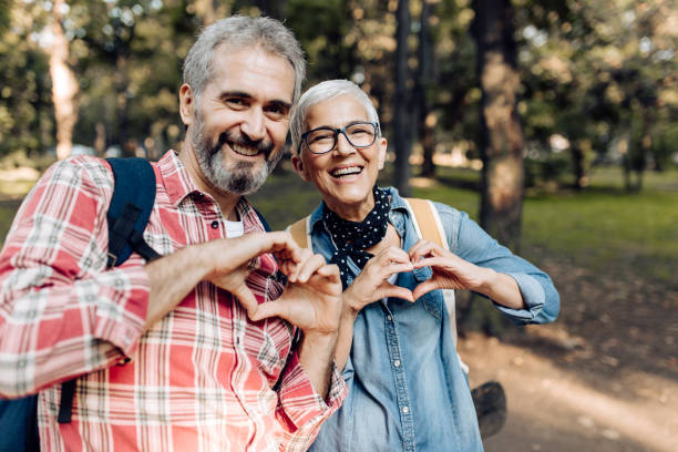 Mature couple on a trip in the nature showing hearts Portrait of a senior couple enjoying their adventurous trip in the nature and showing hearts. heart health stock pictures, royalty-free photos & images