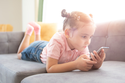 Little girl with mobile phone on couch