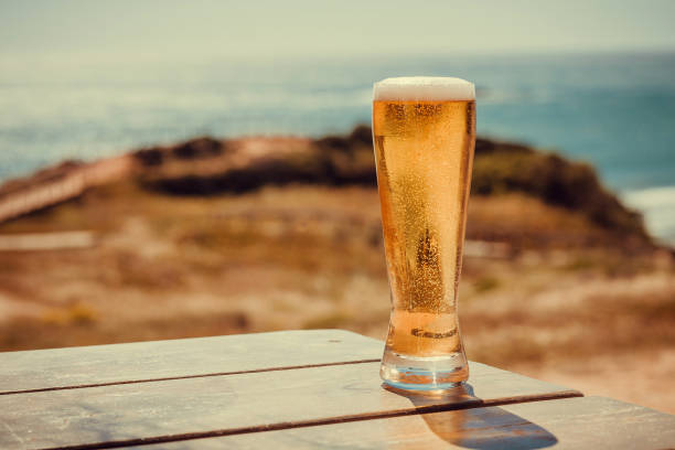 Sunny landscape with beer glass at outdoor bar. Ocean view with fresh drinks on natural background. Vacation concept Sunny landscape with beer glass at outdoor bar. Ocean view with fresh drinks on natural background. Vacation concept. table ledge stock pictures, royalty-free photos & images