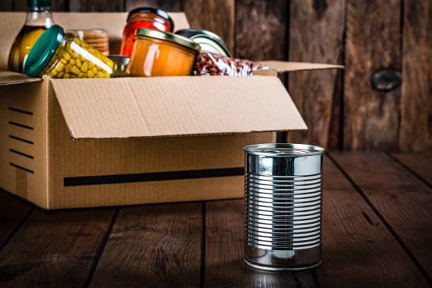 istock Cardboard box filled with non-perishable foods on wooden table. 1283902656