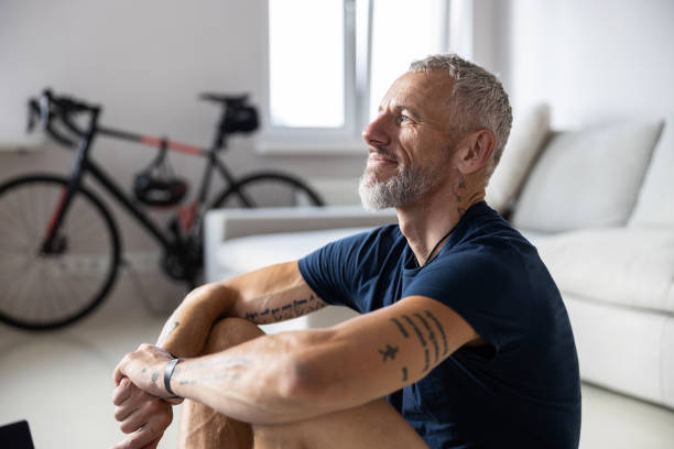 Content man looking hopefully outside the frame Cropped photo of a pleased athlete clasping his hands with tattoos and staring in front of himself man yoga tattoo stock pictures, royalty-free photos & images