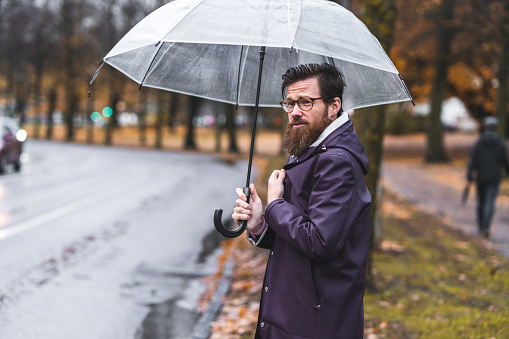 Rear view of an unrecognizable businessman walking down the city streets on his way to the office while it's raining outside.