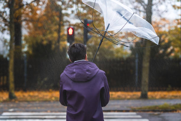 mann mit regenschirm an einem stürmischen tag - das innere nach außen gekehrt stock-fotos und bilder