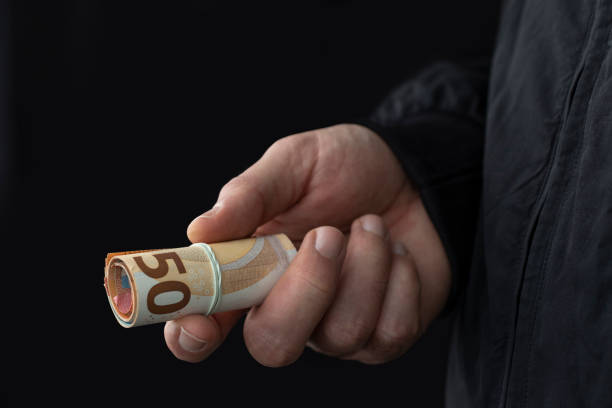 Close up of male hand offering bribe on black background. Close up of male hand offering cash on black background. Illegal smuggling concept. Trafficking stock pictures, royalty-free photos & images