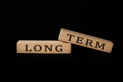 Close-up of Wooden blocks with the words long term. Business investment concept. Isolated on black background