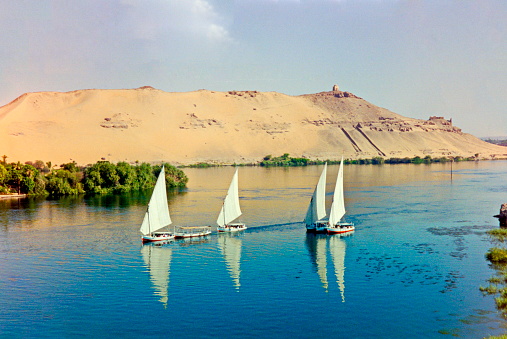 Aswan, Egypt - June 1998. Panoramic Nile view  with the Mausoleum of Aga Khan on the top of the hill at the background. The Aga Khan was buried there two years after he died. The image were scanned from an old negative.