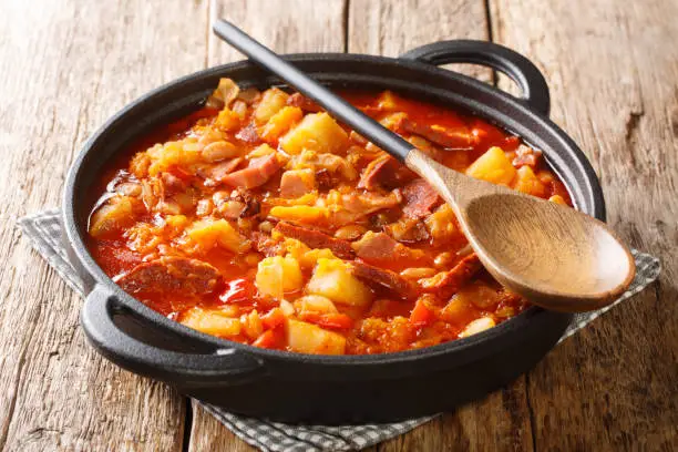 Photo of Delicious organic Locro cooked vegetables, sausages and meat close up in a pot. horizontal