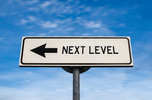 istock Next level road sign, arrow on blue sky background. One way blank road sign with copy space. Arrow on a pole pointing in one direction. 1283912493