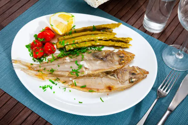 Picture of delicious dish of fried roosterfish with asparagus, tomatoes and lemon